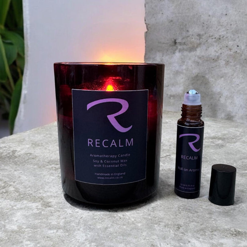 Recalm candle and rollerball bottle on a stone surface with a plant in the background