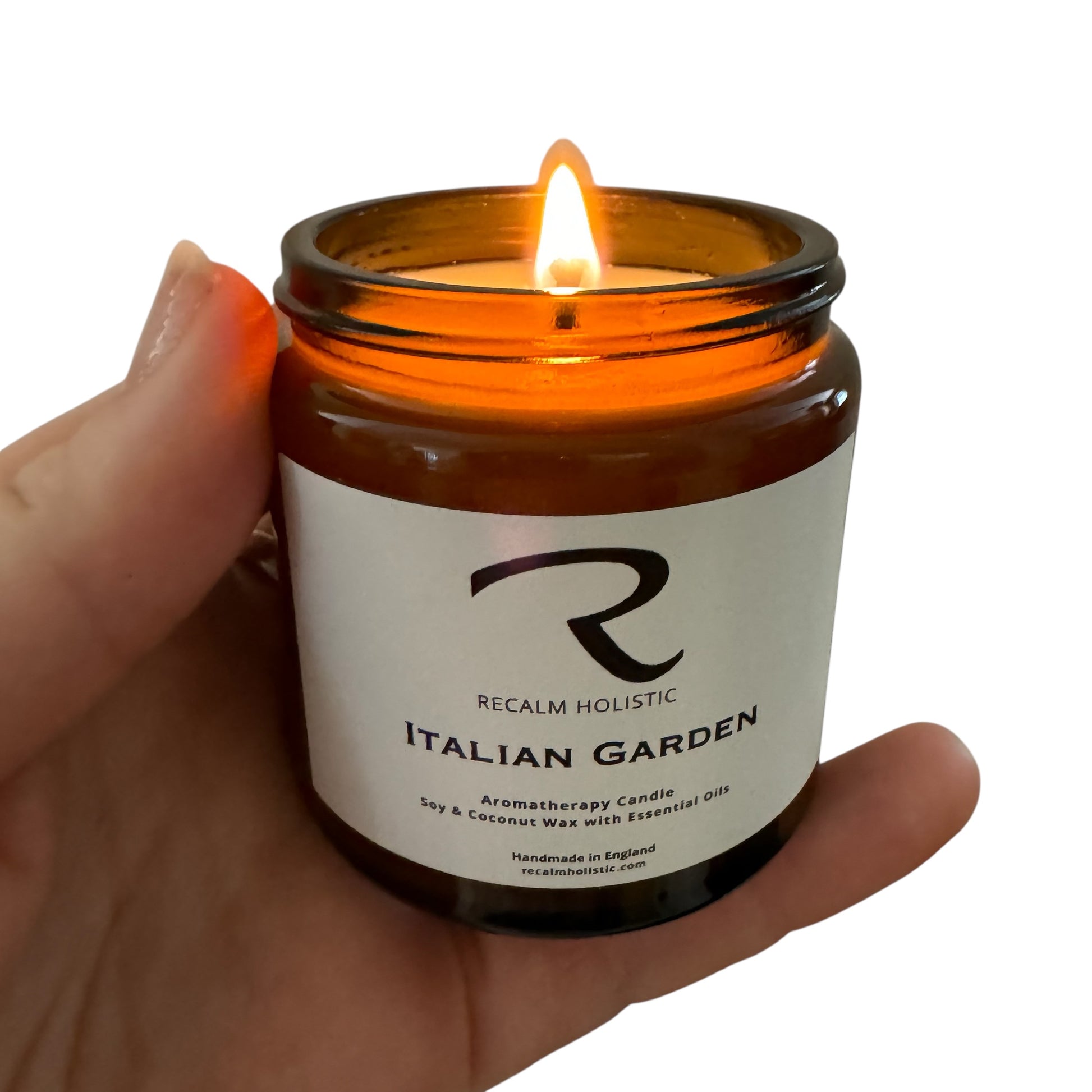 Candle in a jar labeled 'Italian Garden' by 'Recalm Holistic' held in a hand with a white background.