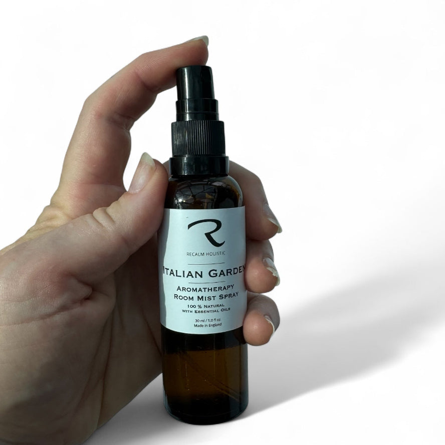 Hand holding a bottle of 'Italian Garden' aromatherapy room mist spray with a white background