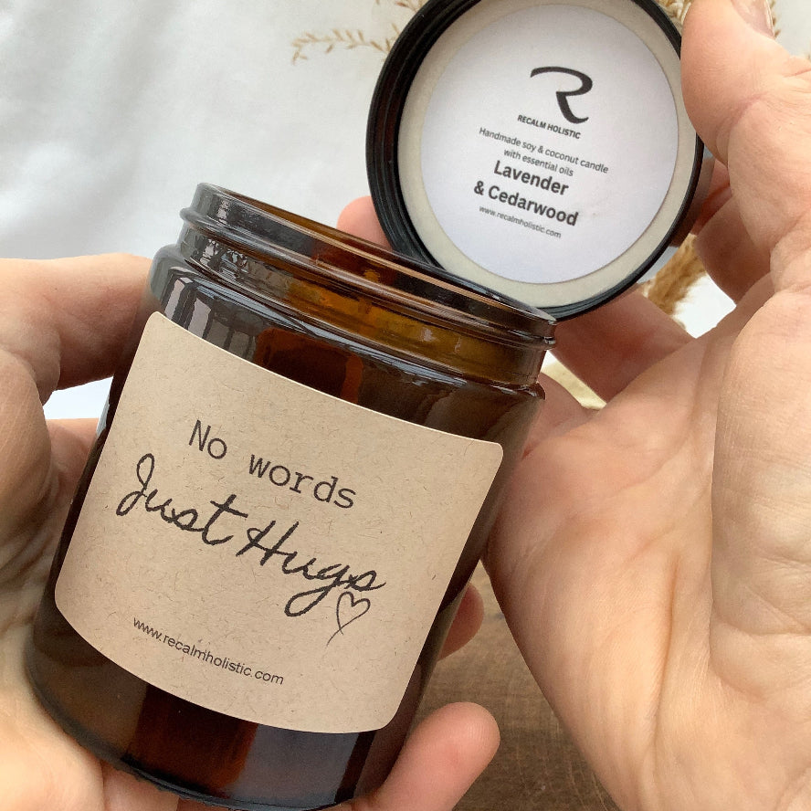 Hand holding a candle jar with a label on saying no words just hugs