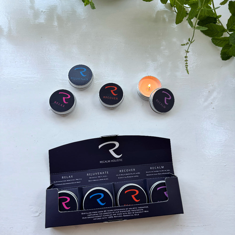 A set of four small round candles from Rocknrollce, including one lit candle and three unlit candles in their black presentation box. The unlit candles feature colorful neon-style 'R' logos in pink, blue, and orange on black lids.