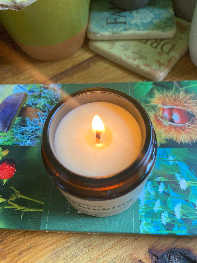 Candle in a jar with a lit wick on a colorful surface