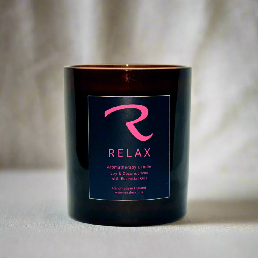 A black aromatherapy candle with a label that reads 'RELAX' in pink letters, indicating the scent is a calming blend.