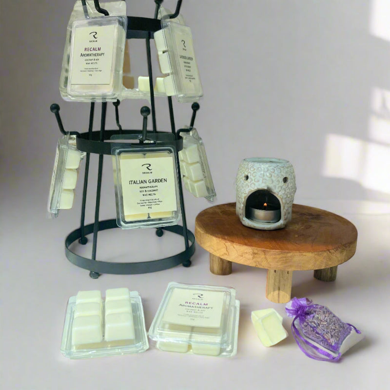A collection of aromatherapy wax melts displayed alongside a wax burner and a selection of boxes, with each melt showcasing a different blend of essential oils.