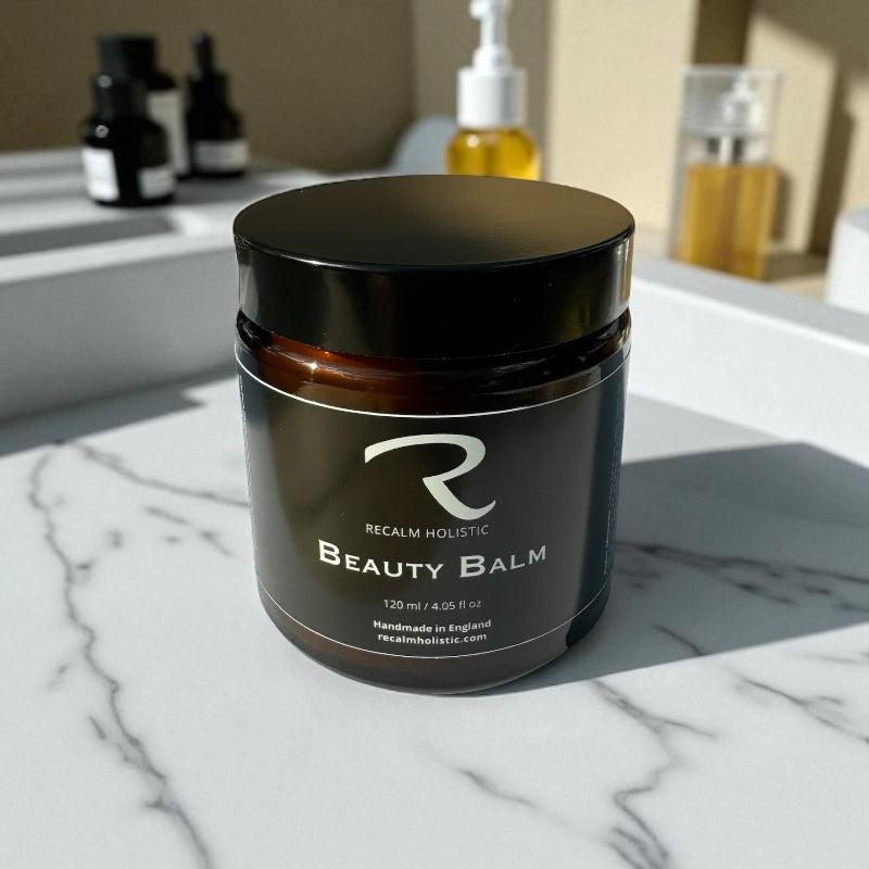 Beauty balm jar with 'Recalm Holistic' branding on a marble surface in bathroom