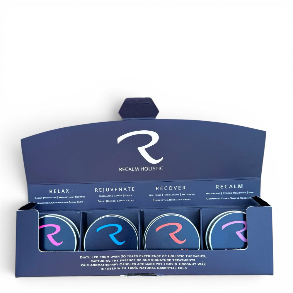 A boxed set of four Recalm Holistic essential oil candles in a navy blue display tray. The packaging features the Recalm Holistic logo and names for the scents: Relax, Rejuvenate, Recover, and Recalm.