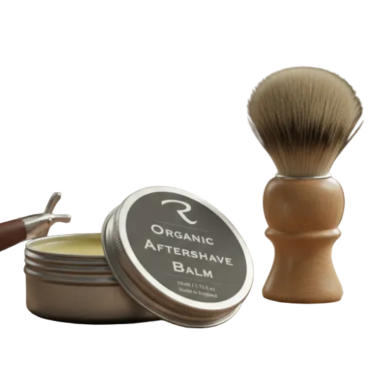 Barber shop setup with organic aftershave balm, shaving brush, and razor on a wooden table, featuring Organic Aftershave Balm by ReCalm Holistic