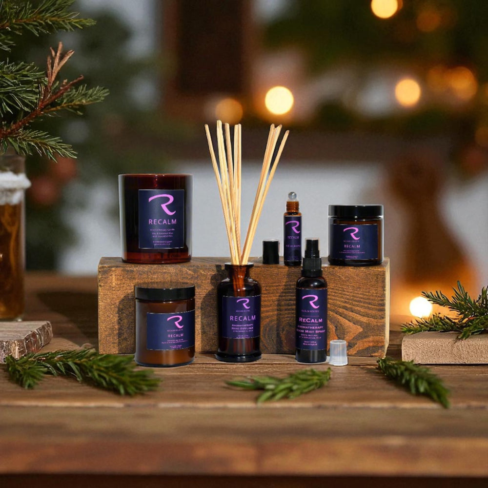 Collection of 'Recalm' products including candles and diffusers on a wooden surface with a festive background, ReCalm Holistic have matching products in their Signature Collection, with Aromatherapy Candle, and matching Reed Diffuser, Room Mist Spray Roll on Aroma for 'Pulse Points' All 100% natural ingredients 
