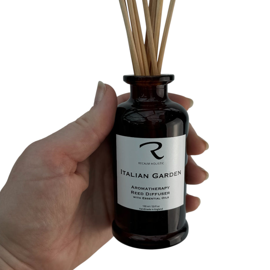 Hand holding a bottle of 'Italian Garden' aromatherapy reed diffuser with a white label.