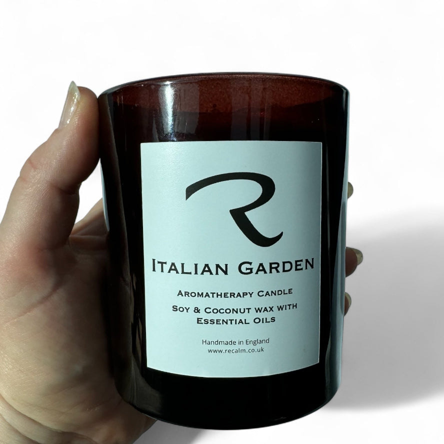 Candle labeled 'Italian Garden' held by a hand on a white background