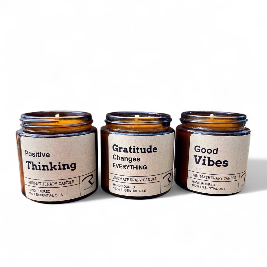 Three aromatherapy candles with motivational labels on a white background