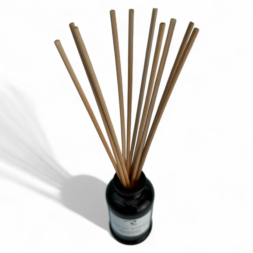 Reed diffuser with wooden sticks in a black bottle on a white background