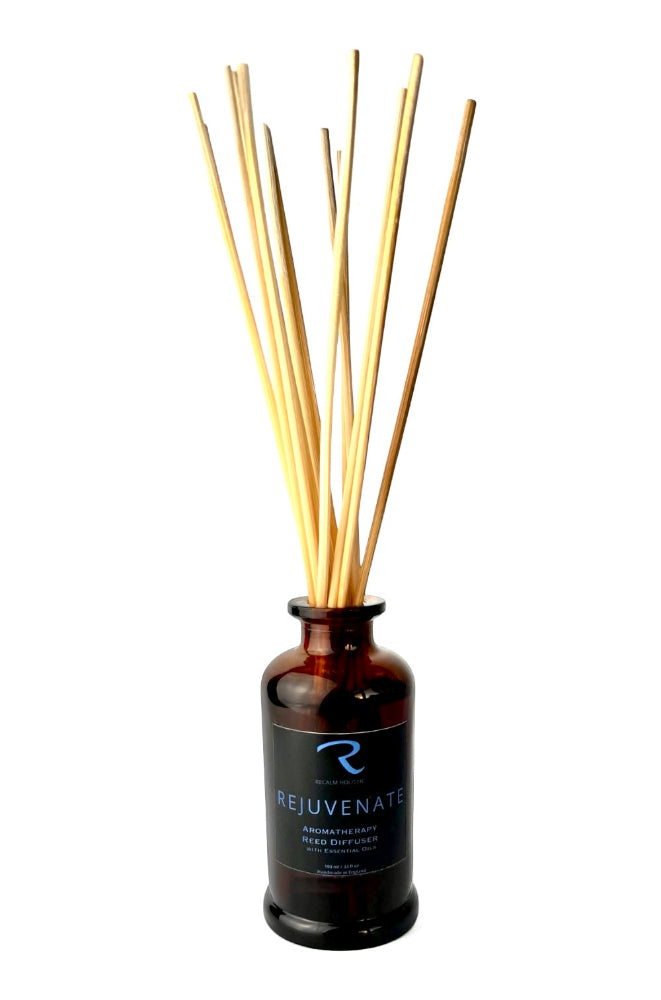 Reed diffuser with wooden sticks in an amber bottle labeled 'Rejuvenate' on a white background by ReCalm Holistic