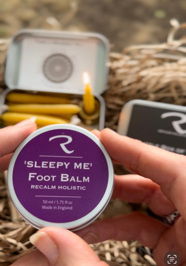 Person holding a 'Sleepy Me' foot balm tin with a blurred background handmade by ReCalm Holistic 