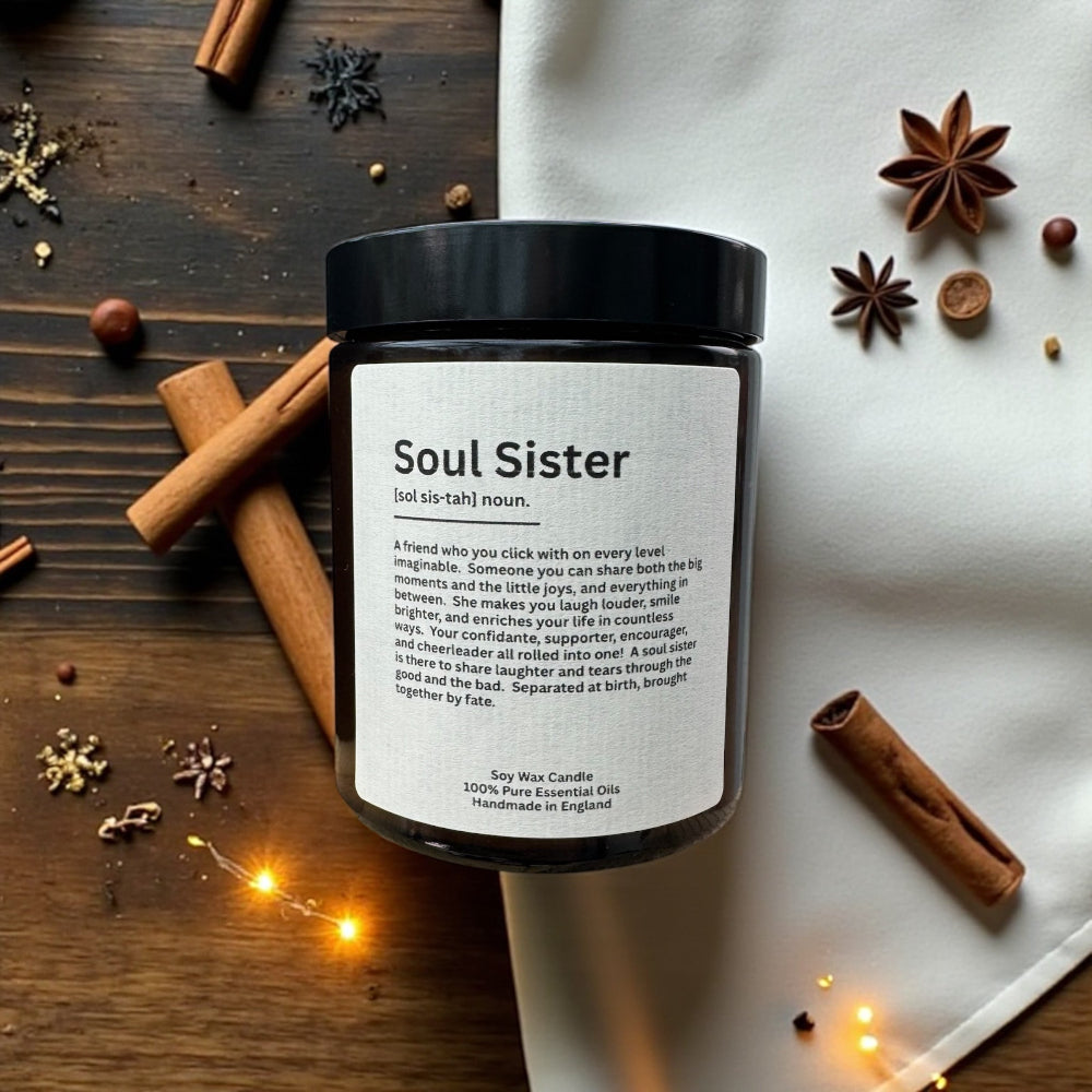 Scented candle jar labeled 'Soul Sister' on a wooden surface with cinnamon sticks and star anise.