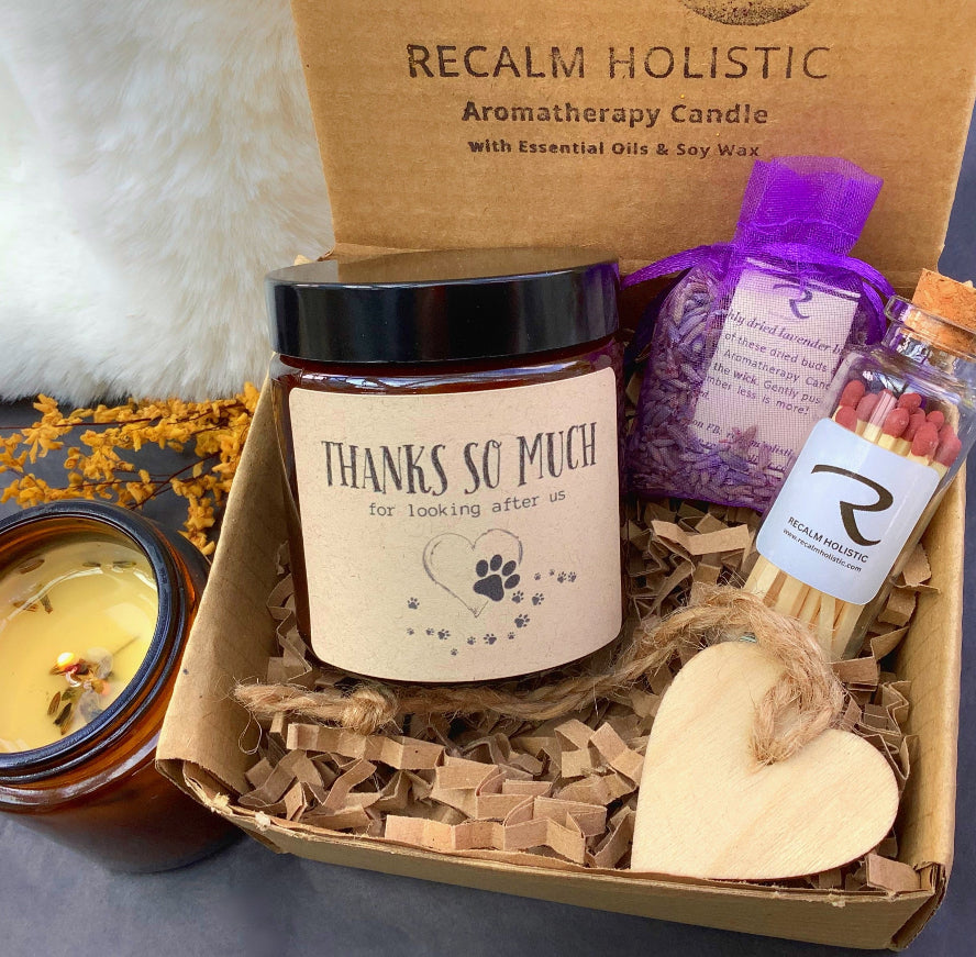 Gift set with candles, essential oils, and a wooden heart in a box labeled 'Recalm Holistic'.
