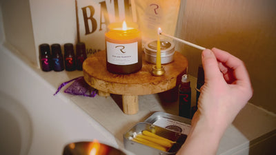 Lighting a ReCalm Holistic natural aromatherapy candle as part of a luxurious weekly self-care ritual in a bathroom setting